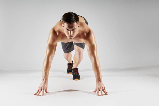 istock Concentrated fit man preparing to run while standing in starting position against white background 1424924290