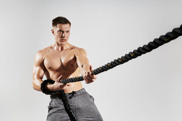 Fit young man pulling a rope against white background stock photo
