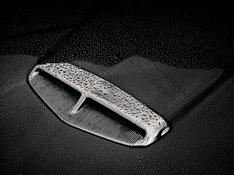 Black and white image of the air intake on the bonnet of a classic car.