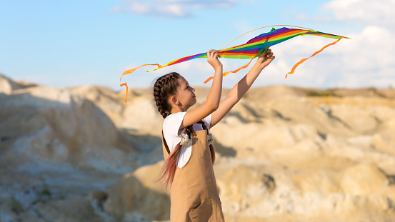A girl of 8-9 years old launches a kite into the sky.