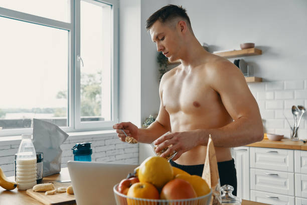 istock Young fit man preparing healthy food while standing at the kitchen 1424927133