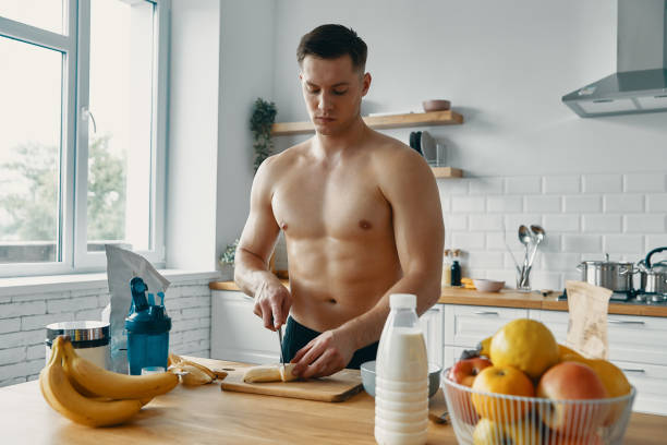 istock Confident fit man preparing healthy food while standing at the kitchen 1424930129
