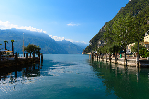 The beautiful Garda lake in Italy, seen from the Piazza ill Novembre square in the city of Riva del Garda, Trentino, Italy. It is a beautiful summer day, with a little bit of clouds.