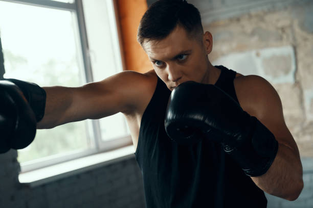 istock Concentrated young man practicing in punching while standing in gym 1424930854