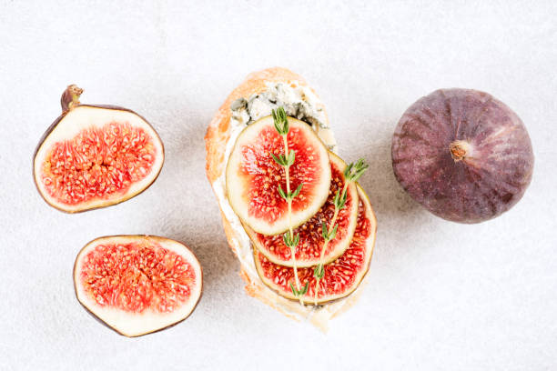 istock Fresh bruschetta with raw fig and blue cheese and ripe figs around over white concrete table background. Healthy Italian breakfast recipe. Top view, selective focus 1424931320