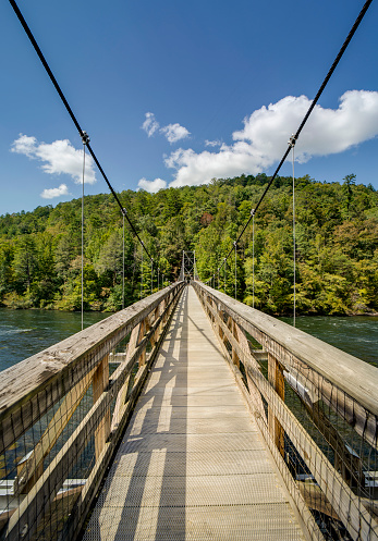 A pedestrian suspension bridge crosses the Hiwassee River in the Tennessee mountains