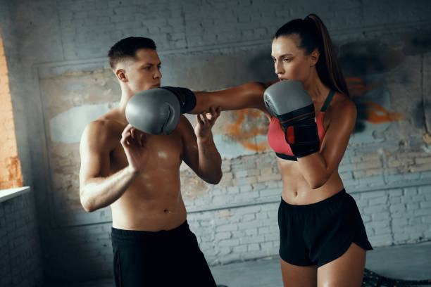istock Fit young woman practicing in punching while her boxing coach teaching her 1424931400