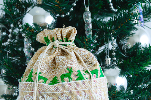 Christmas cotton sack with a deer pattern on the background of a Christmas tree.