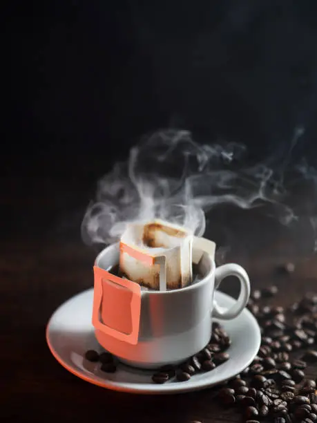 A white cup of freshly brewed drip coffee. Steam from hot coffee