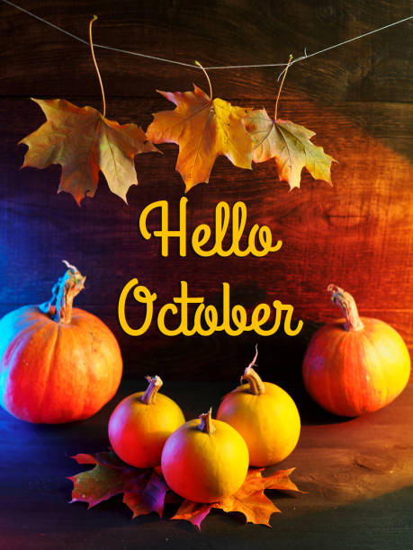 istock Hello October message with pumpkins and autumn leaves on the table 1424934783