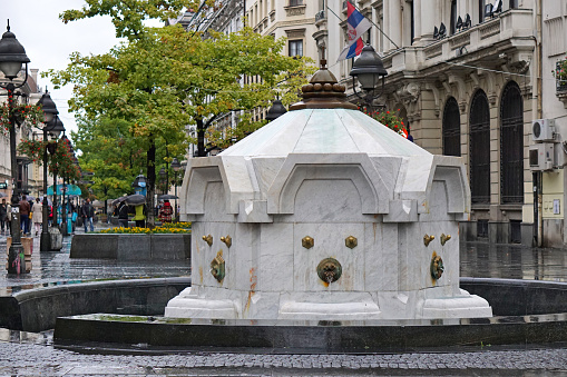 One of the fountains (not operating at the time) in Trafalgar Square, City of Westminster, London. Behind the fountain basin are the National Gallery and St Martin-in-the-Fields church. A sign warns people not to enter the fountain basin.