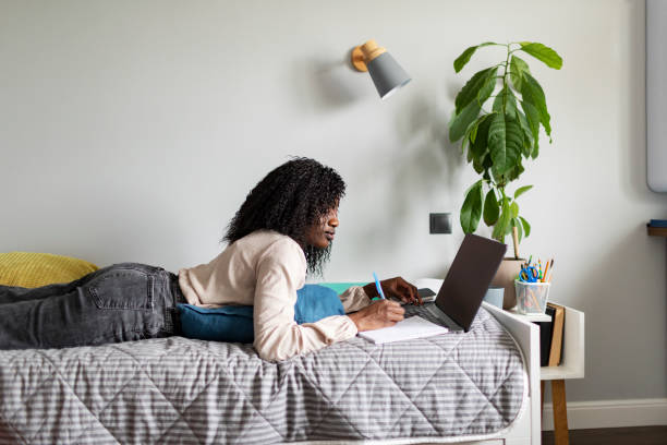 istock Young adult African woman learning at home using laptop 1424940281