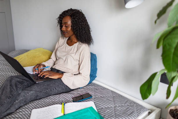 istock Young adult African woman learning at home using laptop 1424940549
