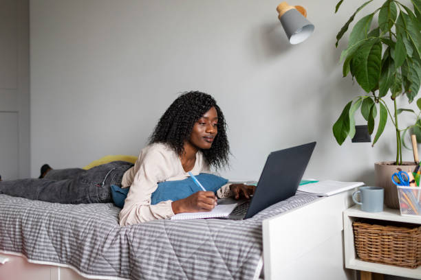 istock Young adult African woman learning at home using laptop 1424940573