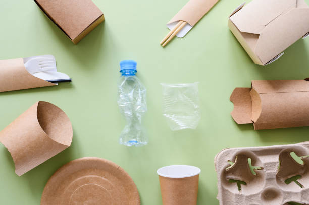 istock Eco-friendly paper utensils and packaging lie around plastic trash on a green background. View from above. The concept of refusing to use plastic. 1424944494