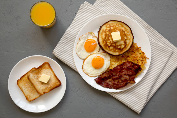 istock Full American Breakfast with Bacon, Hash Browns, Eggs and Pancakes on a plate on a gray background, top view. Overhead, from above, flat lay. 1424946699
