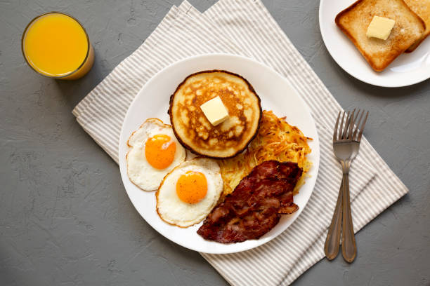 istock Full American Breakfast with Bacon, Hash Browns, Eggs and Pancakes on a plate on a gray surface, top view. Flat lay, overhead, from above. 1424946826