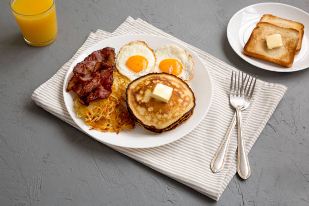 istock Full American Breakfast with Bacon, Hash Browns, Eggs and Pancakes on a plate on a gray background, side view. 1424947002