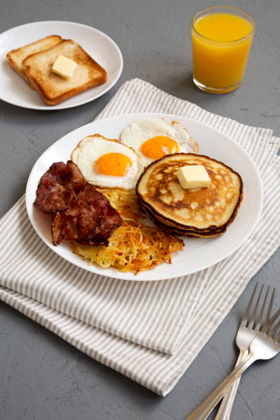 istock Full American Breakfast with Bacon, Hash Browns, Eggs and Pancakes on a plate on a gray surface, low angle view. 1424947298