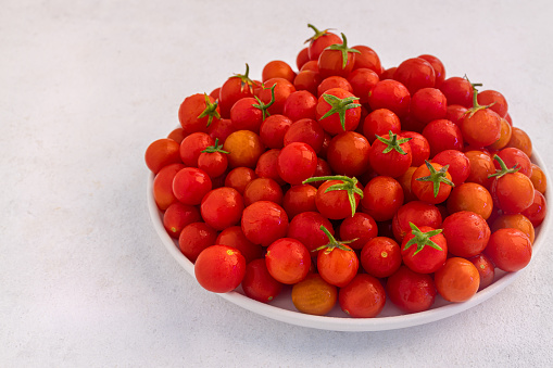 Red cherry tomatoes in a white dish on a light