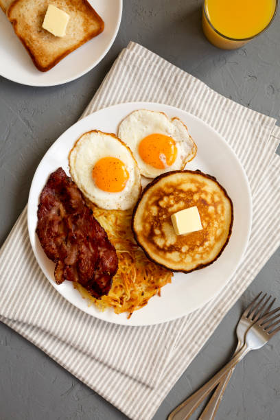 istock Full American Breakfast with Bacon, Hash Browns, Eggs and Pancakes on a plate on a gray background, top view. 1424947453