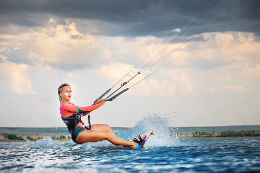 A young woman kitesurfer rides the waves doing a trick. Marine sports. kitesurfing.