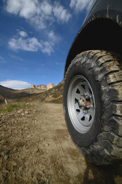 istock Big car wheel on mountains at day backdrop. Offroad 4x4 concept 1424953504