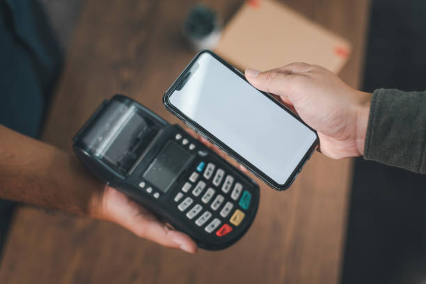 istock Customer pays bills via smartphone using NFC technology. Close-up of a contactless hand-picked payment. man holding a mobile phone to pay bills with contactless technology 1424953848