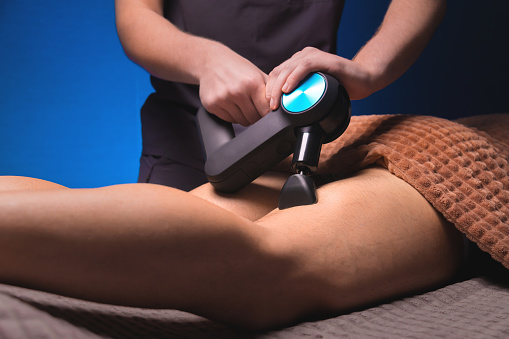 Close-up percussion thigh massage with a special electric device