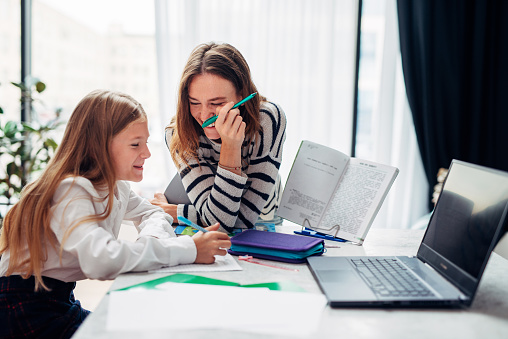 Mother and daughter laughing while doing homework.