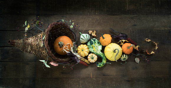 Cornucopia with pumpkins, gourds and holiday decor arranged against an old wood background