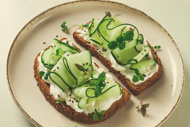 istock Breakfast, cereal bread sandwiches, cream cheese, sliced cucumber, with micro greenery on a light table, close-up, top view, selective focus, no people, 1424962415