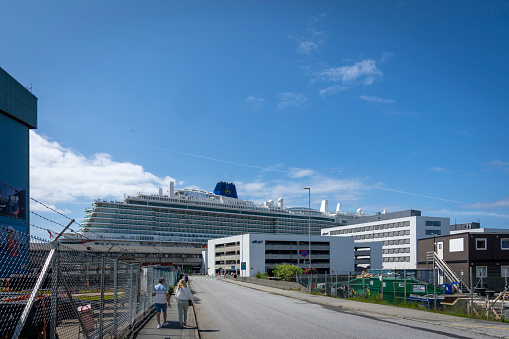 Haugesund Harbour and harbour side buildings, Norway.  There are tourists walking back towards the cruise ship docked in the harbour.