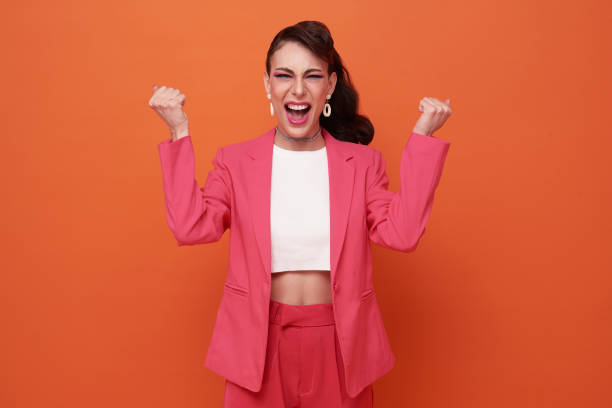 excited young woman standing isolated over orange background make winner gesture. stock photo