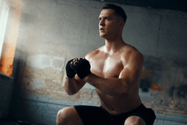 istock Confident young man standing in squatting position while training in gym 1424965754