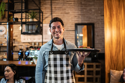 Retrato de camarero llevando un plato terminado en un restaurante photo