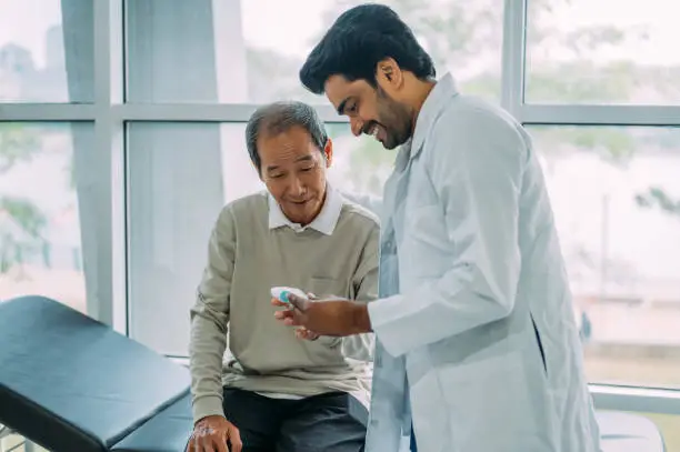Smiling male doctor discussing over medical record with senior man in hospital