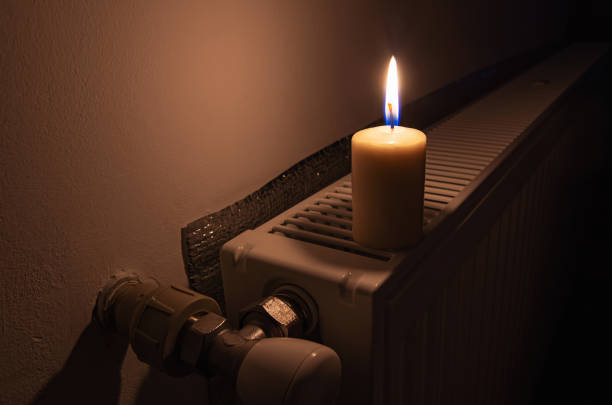 burning candle on the radiator heating in dark home. shutdown of heating and electricity, power outage, blackout. - boiler power station fuel and power generation gas boiler imagens e fotografias de stock