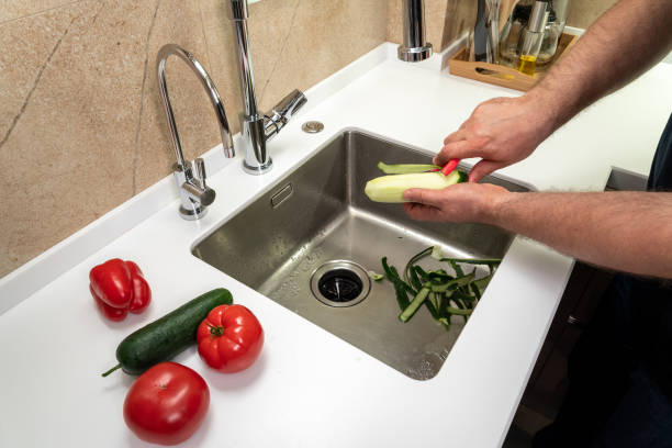 istock Cleaning vegetables in the kitchen in the sink by a man 1424976281