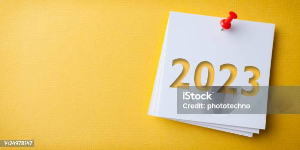 White Sticky Note With Happy New Year 2023 And Red Push Pin On Yellow Cardboard Background Stock Photo - Download Image Now