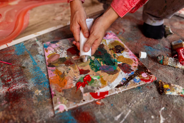 istock Artist adding white paint to paint palette 1424978635