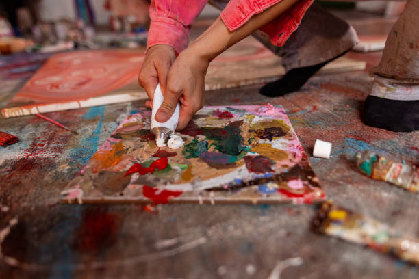 istock Artist adding white paint to paint palette 1424978671