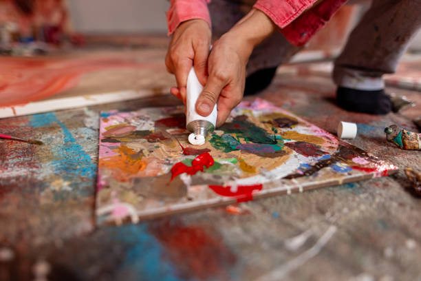 istock Artist adding white paint to paint palette 1424979498