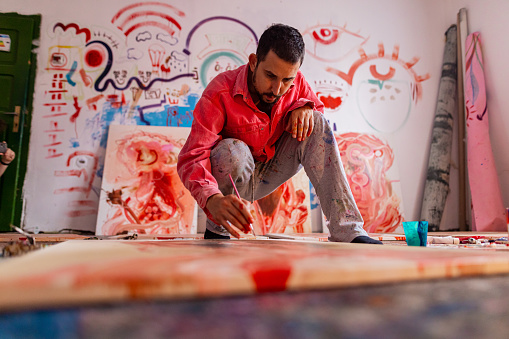 Artist- painter working on painting in studio