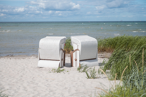 Romantic sea scene at white beach with wicker beach chair at summer sunny day in north Germany