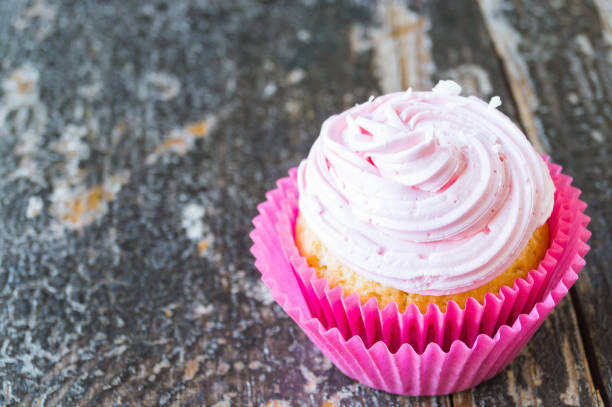 Cupcakes with cream and coconut flakes on a wooden background