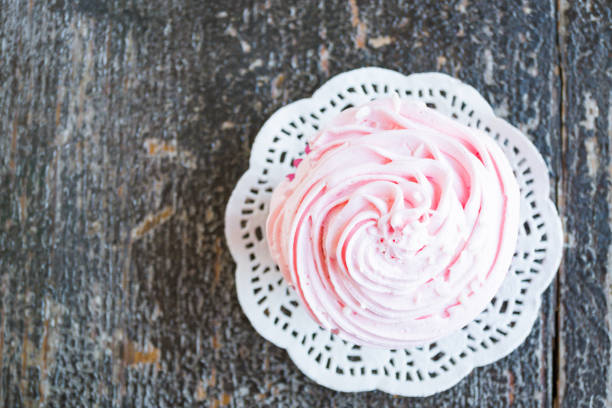 Cupcakes with cream and coconut flakes on a wooden background