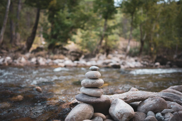 Stack of zen stones in stream leading to a waterfall in a forest Stack of zen stones, Close up of pebble rocks stacked on top of each other in stream leading to a waterfall in a forest, Zen like concepts chan buddhism stock pictures, royalty-free photos & images