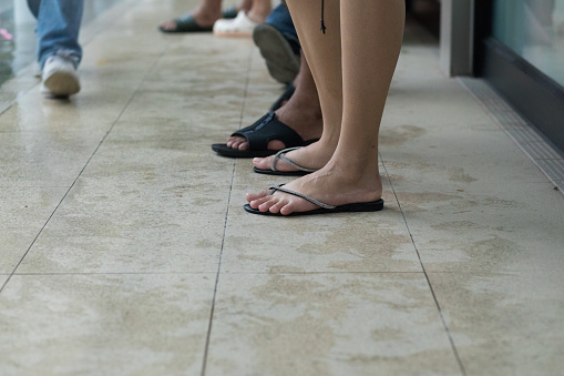 Feet of young thai women in sandals waiting in rain