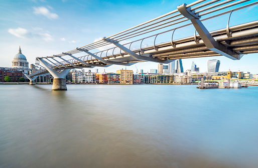 Smooth surface of the flowing river Thames,summer light from setting sun,on the famous iconic bridge, ,blue sky in fine weather,St.Paul's Cathedral and iconic modern city skyline across the water.